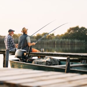 Back view of senior man and his son enjoying in freshwater fishing.