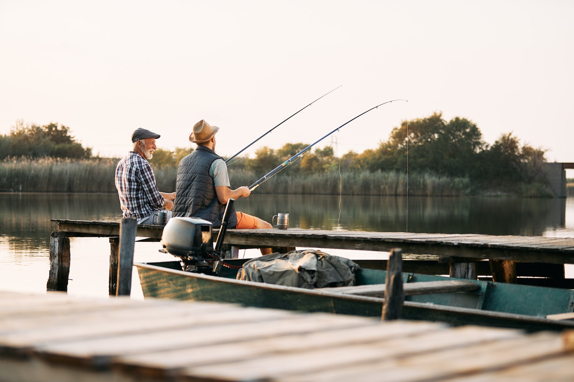 Back view of senior man and his son enjoying in freshwater fishing.